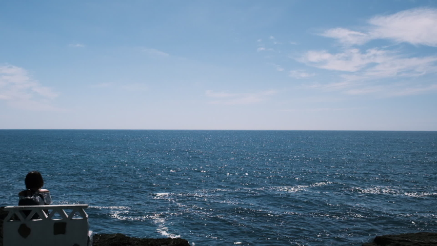 Young couple sitting on a bench admiring the sea view during summer.
