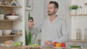 Young Man Talking on Video Call on Smartphone in Kitchen