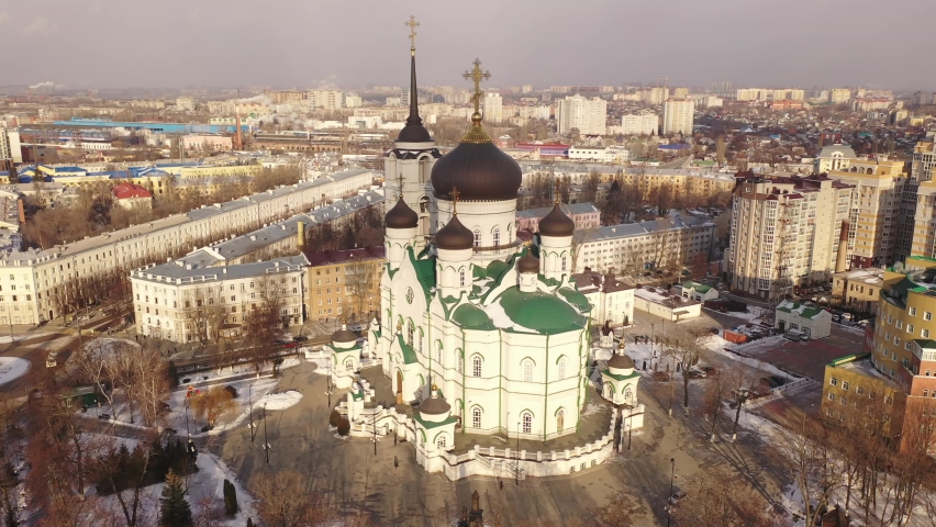 Aerial view of five-domed building of Annunciation Cathedral with attached bell tower in Voronezh on background with winter cityscape, Russia Royalty-Free Stock Footage #1073333015