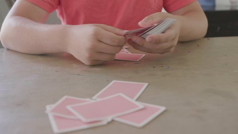 Teen boy playing cards deals cards to camera POV