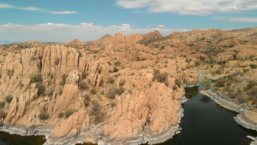 Aerial View of granite dell rocks with hills, cliffs and mountain in the background and watson lake in the foreground