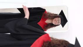 Graduate student rehearse speech in front of mirror, vertical video wear gown and cap mortarboard at home Spbi.
