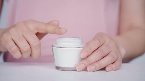 Closeup shot of mid age woman hands, taking face cream for older skin with fingertip. Advertising of antiwrinkle antiaging whitening rejuvenation uv protection women in menopause treatment.