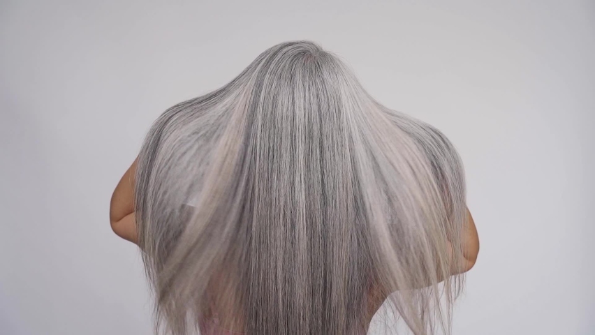 Slow motion of gorgeous middle aged mature woman, senior older 50s lady waving grey silver hair isolated on white background. Back view. Slow motion. Ads of hair care spa, hair loss prevention cure. Royalty-Free Stock Footage #1073342300