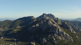 View from above, stunning aerial video shoot by a drone flying over some granite mountains during sunset. San Pantaleo, Sardinia, Italy.
