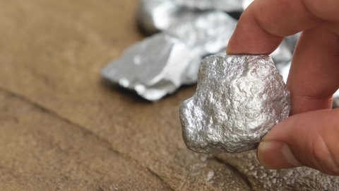 Miners hold platinum or silver in their hands found in mines for consideration.