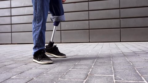Young man with prosthetic leg walking on pavement