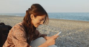 Girl draws uses the smartphone on the beach