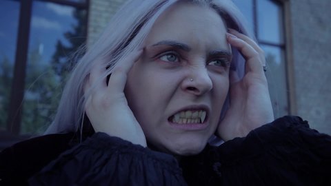 Vampire woman screams showing teeth. She suffers and screams in horror.