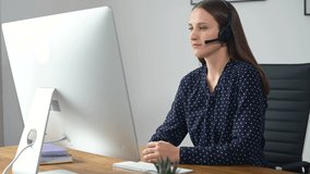 Headshot of smiling young female employee wearing wireless headset, looks at camera, cheerful woman in headphones takes a call from colleagues or clients online, working remotely from home office