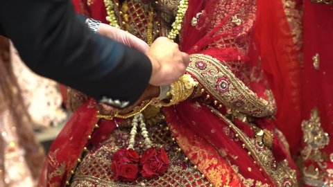 Groom tying cultural sacred thread on bride’s hand at a traditional Indian wedding. Indian wedding ritual. 
