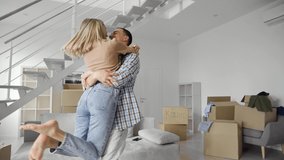 Happy young family couple embracing kissing in new home relocation. Joyful family in living room at moving day, boxes on background, first time home owners concept. Slow motion. - Powered by Shutterstock - Get 15% off with code: PIKWIZARD15