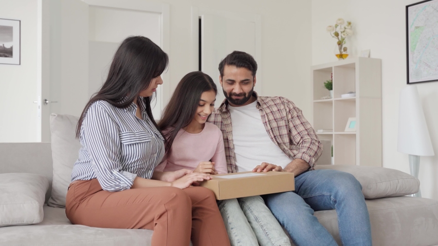 Happy excited indian family parents with teenage daughter unpacking parcel postal shipping box receiving shipment from online shop sitting on sofa in living room. E commerce online shopping concept. | Shutterstock HD Video #1073362691