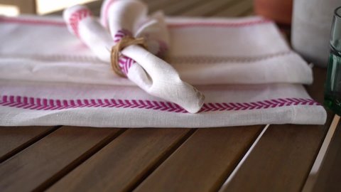 White napkins with pink and light green edges, or pink and light green napkins served on the table with cuttlery with wooden  handles. 