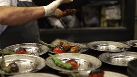 Close-up slow video of chicken kebab from skewer in restaurant and putting it on iron plates