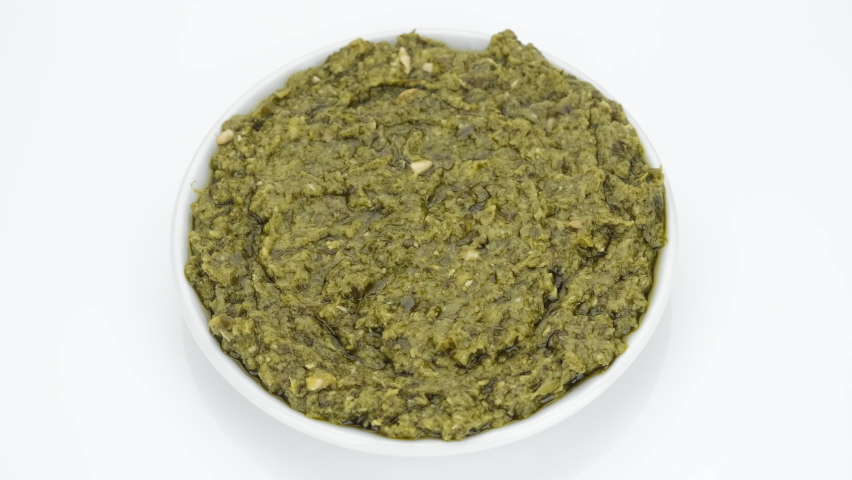 Traditional Italy pesto sauce isolated on white background, rotating. Pesto alla genovese. 4K UHD video