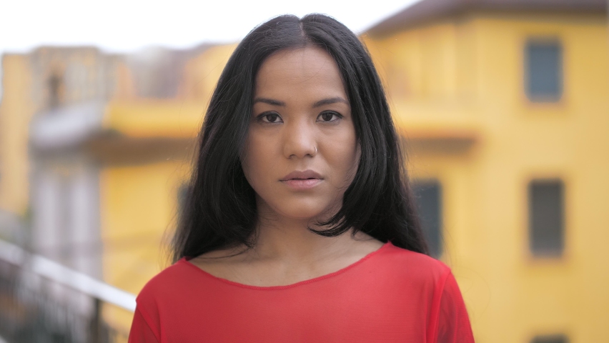 young serious indian woman on the roof staring at camera toughtfully