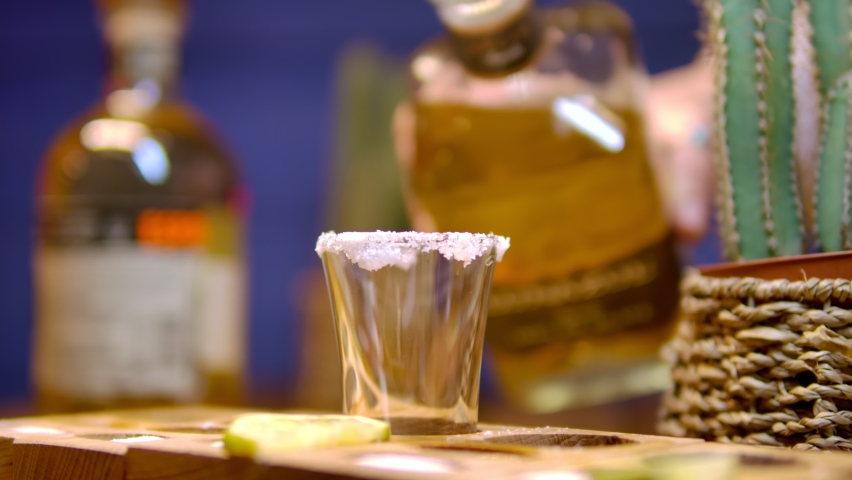 Traditional drink from Mexico tequila.  The bartender's hand pours cold tequila from a bottle into a shot. Party time. Time to drink Royalty-Free Stock Footage #1073372444