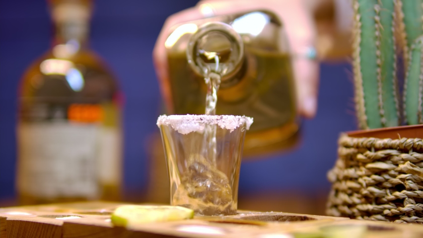Traditional drink from Mexico tequila.  The bartender's hand pours cold tequila from a bottle into a shot. Party time. Time to drink | Shutterstock HD Video #1073372444