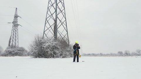 Electrical engineer servicing pylon electrical faults in snowstorm blizzard