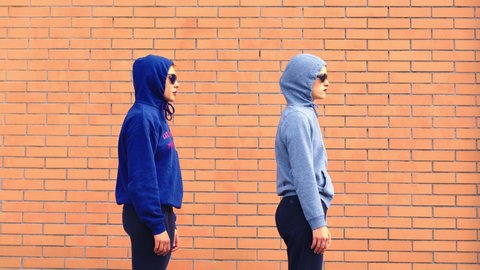 hooded girls wearing sunglasses dance in front of the camera in hip hop style