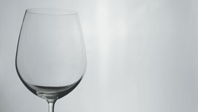 Close-up video with copy space of expensive red wine pouring in vivid glass wine with white background and lighting in studio shows refreshing alcoholic drink for luxury dinner in winery and party.