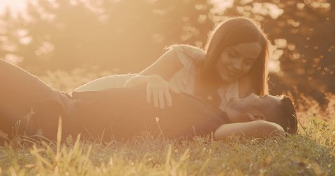 Couple lovers hugging and kissing in the park at sunset. Love, youth, happiness concept. Health care, authenticity, sense of balance and calmness. Sustainable energy. 4K slow motion
