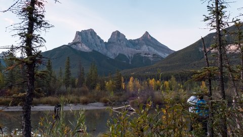 Time-lapse Zoom out of Group of photographer taking a photo at Three Sisters Mountains are rocky mountains in autumn forest at Canmore, Banff national park, Canada