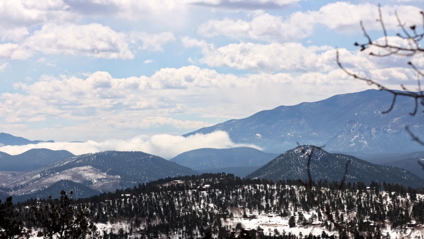 Partly cloudy and low clouds building during a timelapse during the spring with snow on the ground, viewing the Lost Creek Wilderness and Pike National Forest in the Rock Mountains, Colorado, USA.