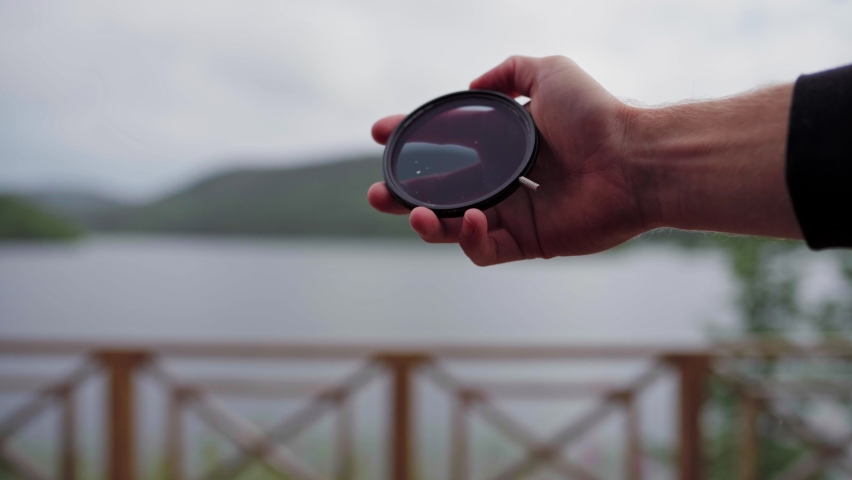 Hand Holding A Tinted Glass At The Balcony Near Riverside In Norway. -close up