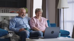 elderly married couple is communicating by online video chat with friends or children, retirees are sitting together at home