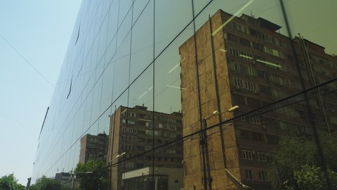 4K Outside view of business district building or shopping mall with wall mirror windows at the  day. Sunlight . Reflection of city , cars and towers in  mirrored walls . Drone camera moving 