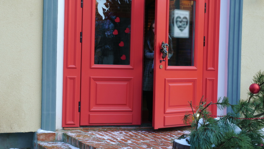 A young woman is leaving a cafe or a bookstore with a book in the hand. A concept of Saint Valentine s Day or Christmas