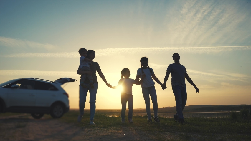 People in the park. happy family a silhouette walk at sunset. car travel kid dream concept. happy family parents and children walk silhouette next to car. family walk next to sun car