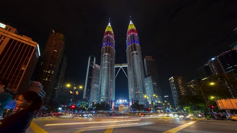KUALA LUMPUR - AUGUST 30: Traffic light trails and pedestrians near The Petronas Towers at night of August 30, 2020 in Kuala Lumpur, Malaysia. Time lapse. Zoom in motion timelapse.