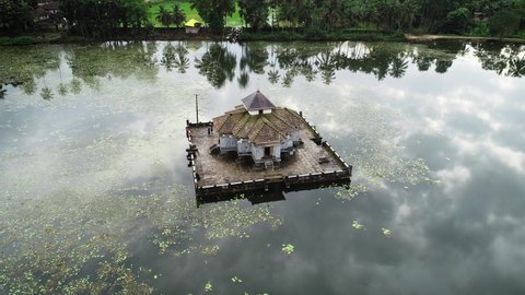 Aerial orbiting shot of beautiful Varanga Jain Temple in island surrounded by lake with waterlilies. Holiday trip in India.