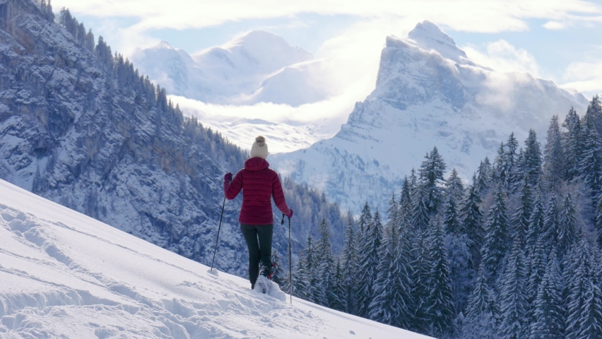 A Beautiful young woman is snowshoeing in a white snow covered valley in the French Alps, towards the Mont Blanc in the background, Samoëns Haute-Savoie