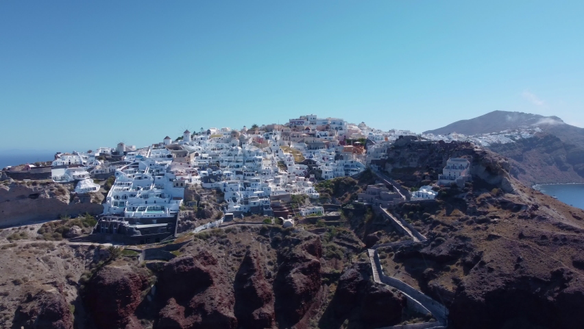 Flight over of traditional terraced white villas ini village Oia, Santorini, Greece