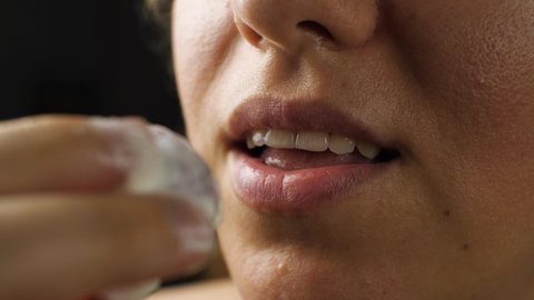 Close-up of a woman biting a strawberry with cream. Cream marks remain on the lips. Girl wipes her lips with her finger