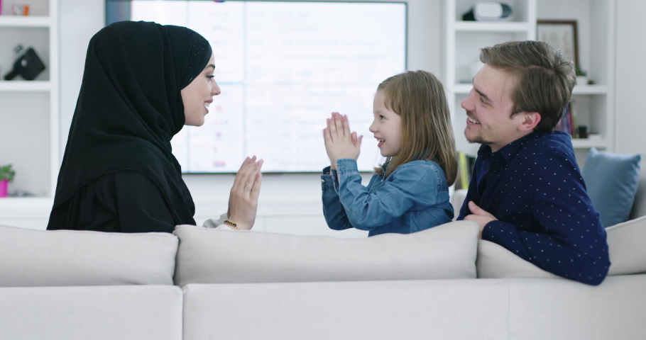 muslim famliy at home playing games on sofa with their kid