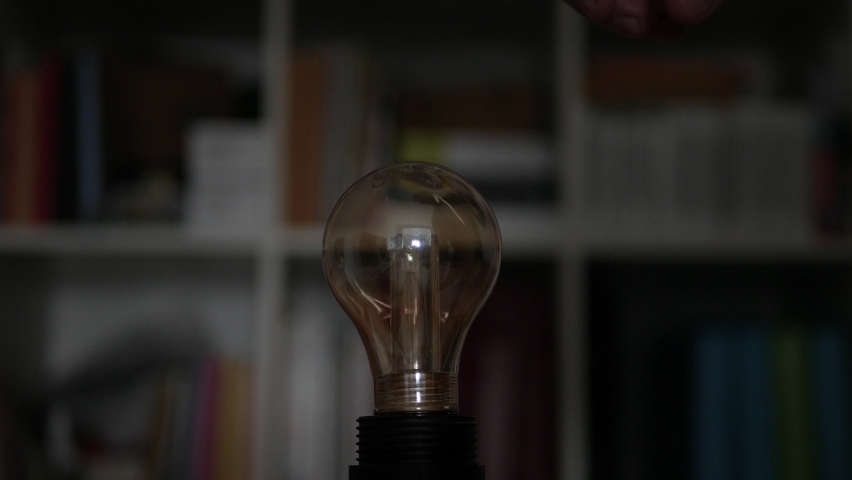 A Hand Turning On a Light in the Room, Screwing in a Socket One Incandescent Light Bulb with Warm Light. Royalty-Free Stock Footage #1073419649