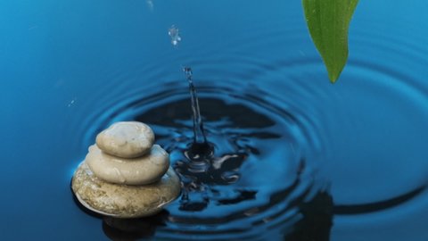 Slow motion. Harmony. drop of rain falls into blue water with a white pyramid and a green leaf. Spa background. Lifestyle