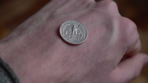 Man Shows A Quarter Dollar Coin On The Back Of The Fisted Hand. close up