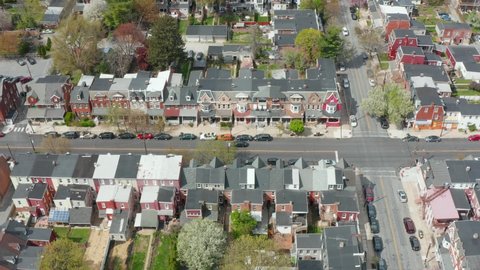 Aerial tilt up reveals residential urban housing district in USA. Light traffic on city streets. Many homes and houses.