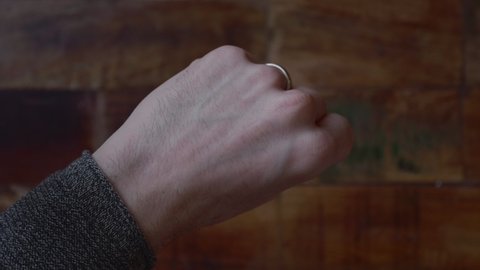 Man Reveals The Coin At The Back Of His Hand with Wooden Floor On The Background. close up