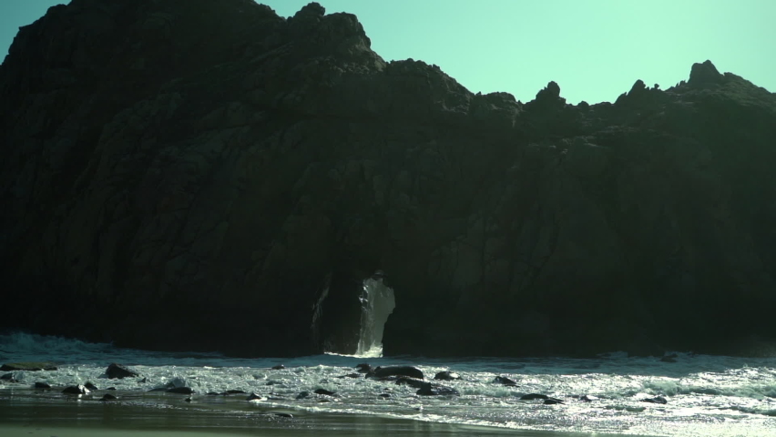 Waves coming through the hole at Pfeiffer Beach Arch, slow motion, daytime footage.