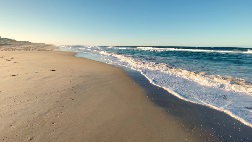 Beautiful sunny day on a calm pristine beach with blue skies in North Carolina in the Outer Banks in Nags Head during early summer | Shutterstock HD Video #1073428973