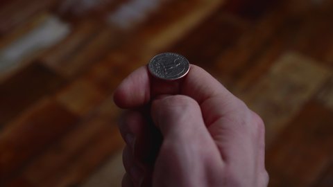 Man Snaps A Quarter Dollar Coin In The Wooden Floor Using His Thumb. close up