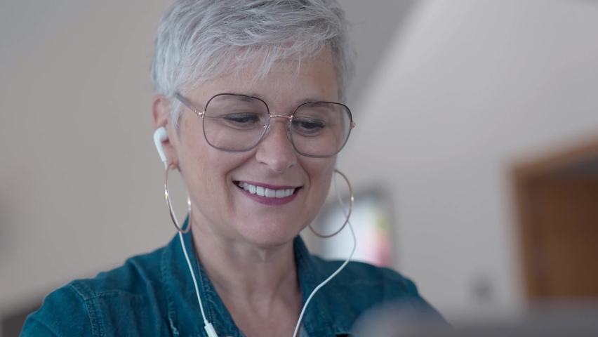 portrait of a 55 year old senior woman working on her laptop in her home