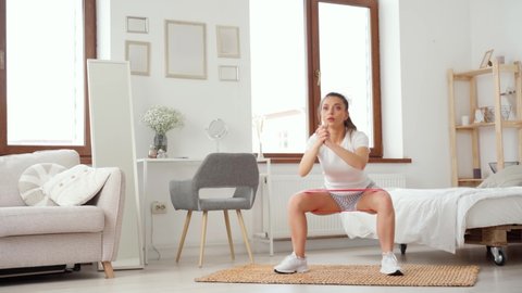 Sporty woman does squats in a room, home fitness exercises